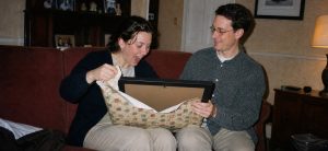 Adult unwrapping a personalised gift in a black frame in a late-1990s-style living room