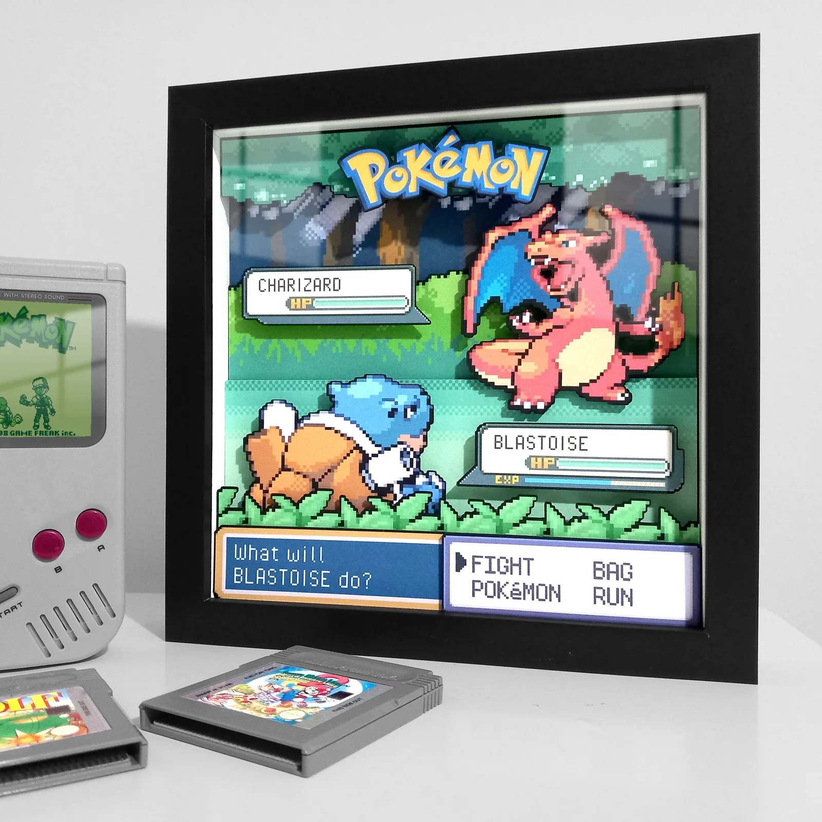 Custom Charizard and Blastoise Pokémon battle shadow box displayed beside a retro Game Boy and cartridges.