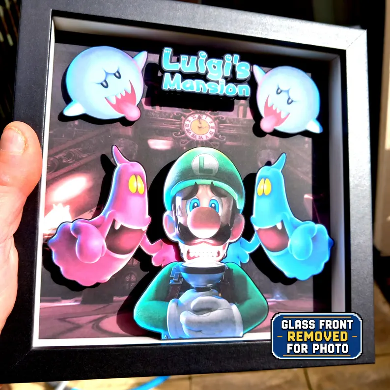 Luigi's Mansion shadow box held in one hand with the glass front removed to show the depth of the cardstock layers.